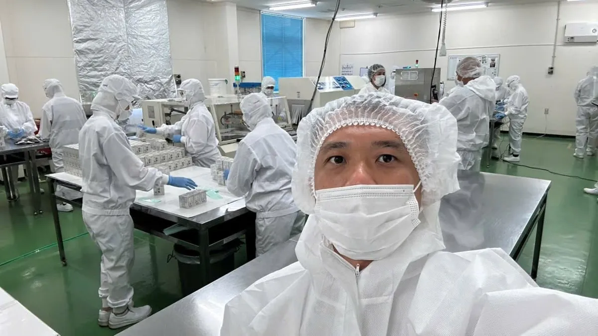 Phan Hồng Sơn mặc đồ bảo hộ trong xưởng đóng gói nhà máy AFC-HD AMS Life Science, Shizuoka, Nhật Bản